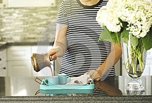 A woman is pouring coffee in a cups