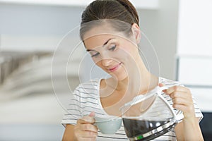 Woman pouring coffee into espreso cup photo