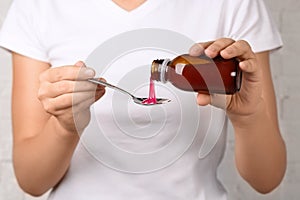 Woman pouring cough syrup into spoon