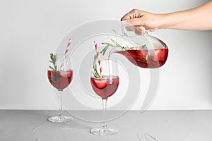 Woman pouring cranberry cocktail into glas