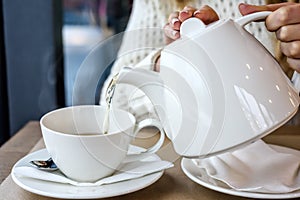 Woman pouring a Cup of hot steaming tea in the restaurant. Winter leisure, cold weather, drink