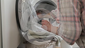 Woman pouring detergent gel into cap and put into washer machine, close the door and start washer. Washer machine and