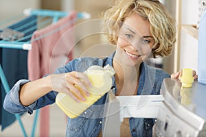 woman pouring fabric conditioner into washing machine drawer