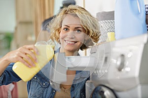 woman pouring fabric softener into washing machine drawer