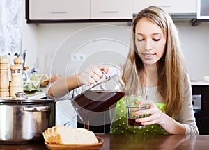 Woman pouring fresh kvass in glass