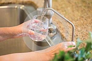 Woman Pouring Fresh Reverse Osmosis Purified Water Into Glass in photo
