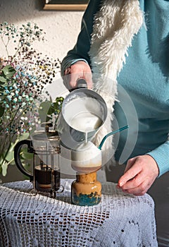 woman pouring frothed milk coffee into morning coffee with tapioca for breakfast