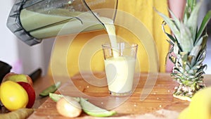 Woman pouring fruit smoothie in drinking glass