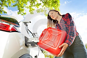 Woman pouring fuel into gas tank of a car from can