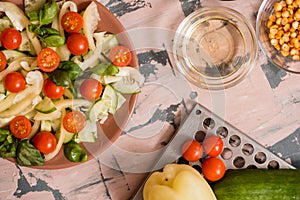 Woman pouring honey mustard dressing into bowl with fresh salad on table