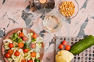 Woman pouring honey mustard dressing into bowl with fresh salad on table