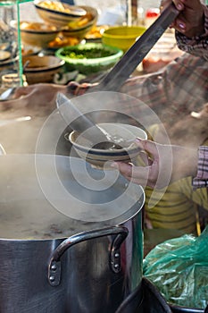 Woman pouring hot porridge into the bowl at street food stall