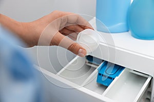 Woman pouring laundry detergent into drawer of washing machine, closeup