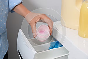 Woman pouring laundry detergent into drawer of washing machine, closeup