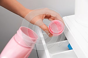 Woman pouring laundry detergent into drawer of washing machine, closeup