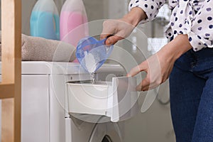 Woman pouring laundry detergent into washing machine drawer in bathroom, closeup