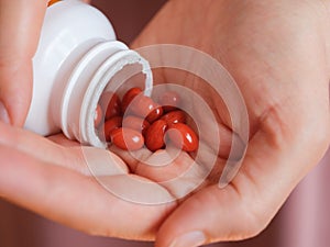 A woman pouring Lutein softgels out of a bottle into the palm of her hand