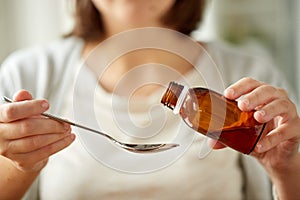 Woman pouring medication from bottle to spoon