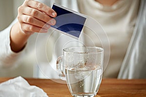 Woman pouring medication into cup of water