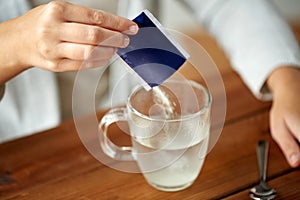 Woman pouring medication into cup of water