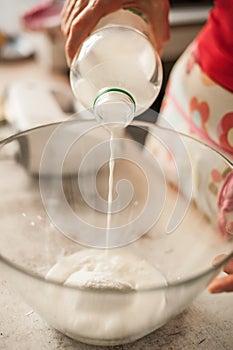 Woman pouring milk into glass bowl and making whipped cream