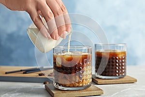 Woman pouring milk into glass with cold brew coffee