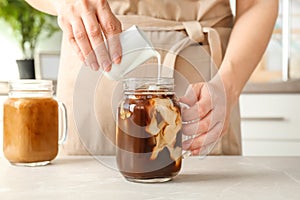 Woman pouring milk into mason jar with cold brew coffee