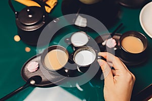 Woman pouring milk in mug of tea from kettle.