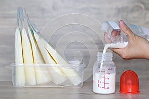 Woman pouring milk in to bottles for new baby on wooden table