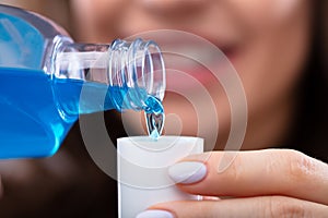 Woman Pouring Mouthwash Into Cap