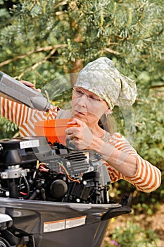 Woman pouring oil into outboard motor