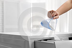 Woman pouring powder into drawer of washing machine indoors, closeup with space for text.