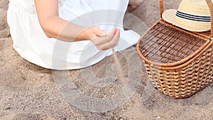 Woman pouring sand from the fingers on the beach. Sand in hands. Concept of vacation, picnic and trip