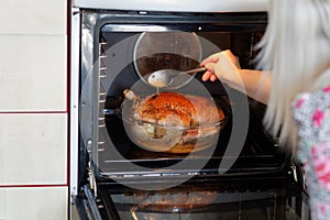 Woman pouring sauce on roasted duck