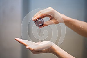 Woman pouring shampoo from bottle into hand