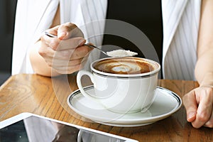 Woman pouring sugar into coffee cup. Sugar addicted.