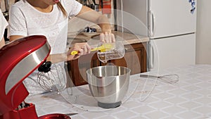 Woman is pouring syrup in mixer bowl to cook cream for cake.