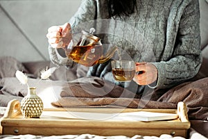 Woman pouring tea in mug from glass teapot. Cozy home hygge style interior. Breakfast still life