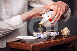 Woman pouring teacup in traditional chinese teaware.