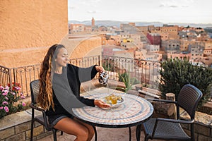 Woman pouring traditional moroccan mint tea on terrace with amazing view