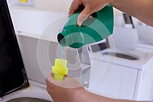 Woman pouring washing powder into the washing machine tank