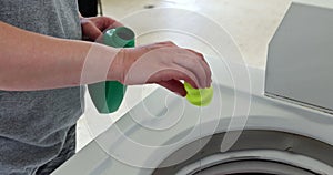 Woman pouring washing powder into the washing machine tank