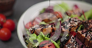 Woman pours balsamic sauce on a salad and Sliced Fried grilled pieces of Organic Tuna Steak in a plate