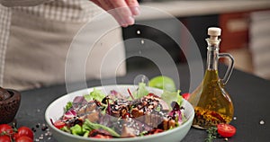 Woman pours balsamic sauce on a salad and Sliced Fried grilled pieces of Organic Tuna Steak in a plate