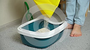 A woman pours bentonite clumping clay litter into the cat toilet