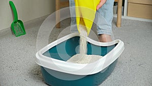 A woman pours bentonite clumping clay litter into the cat toilet