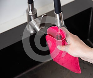 A woman pours hot water into a medical heating pad from the tap. Treatment of diseases with heat, close-up
