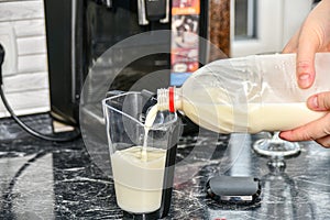 A woman pours milk into a container for making espresso or cappuccino coffee