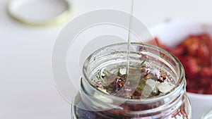 A woman pours olive oil over sun-dried tomatoes in a jar. Cooking at home. Close-up shot