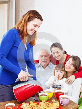 Woman pours tea from teapot for family